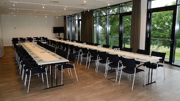 A conference room with a long table, black chairs, and large windows.