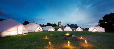 Un terrain de camping avec plusieurs tentes et un foyer central.