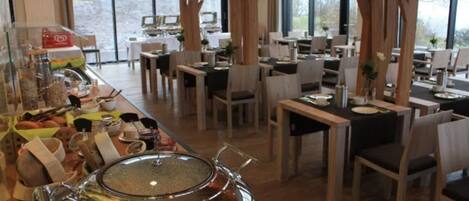 A restaurant with multiple dining tables and chairs, large windows, and a buffet area with various food items.