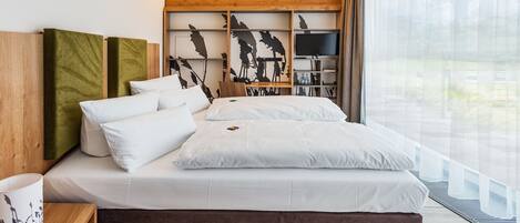 Un dormitorio moderno con una cama grande, cabecera de madera, televisión y vistas al exterior.