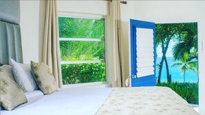 A bedroom with a bed, a window with curtains, and a view of a tropical beach through a door. - Kaliko Beach Club - All Inclusive Resort (Arcahaie)