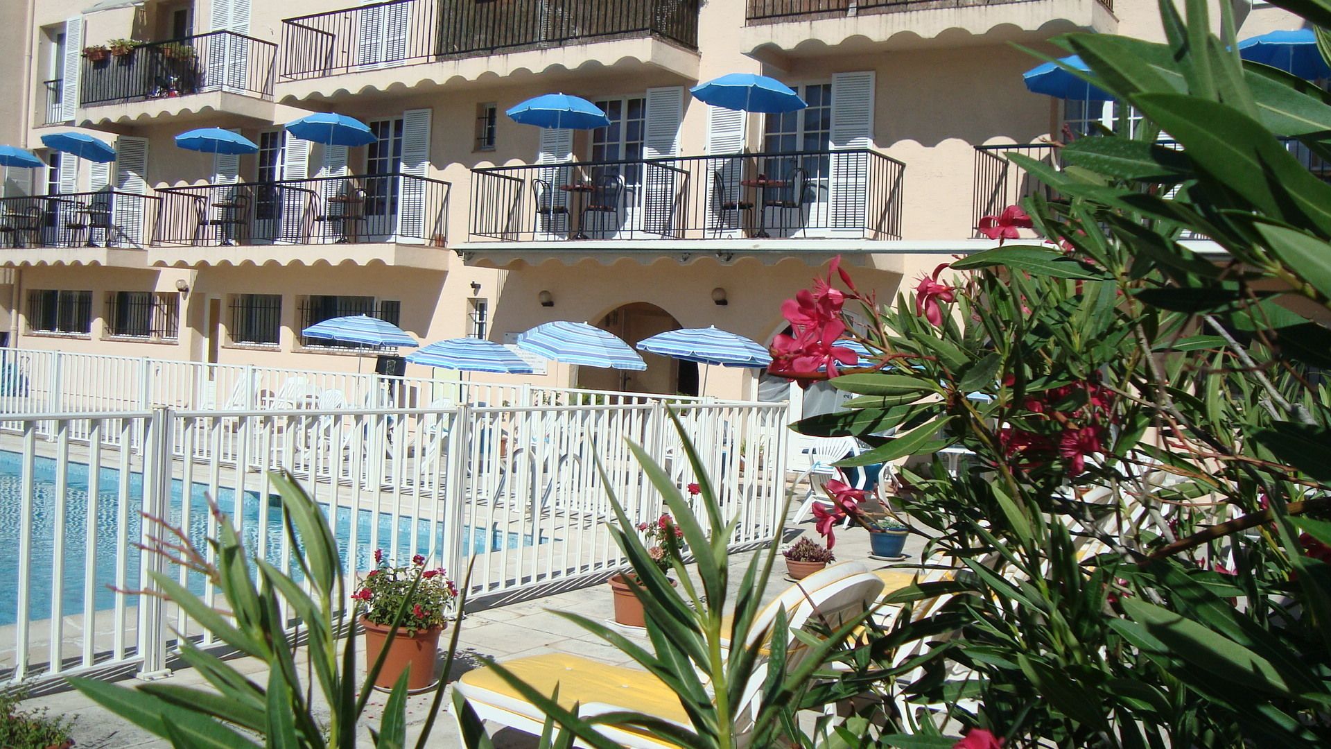 A hotel with multiple balconies, outdoor seating, and a swimming pool.