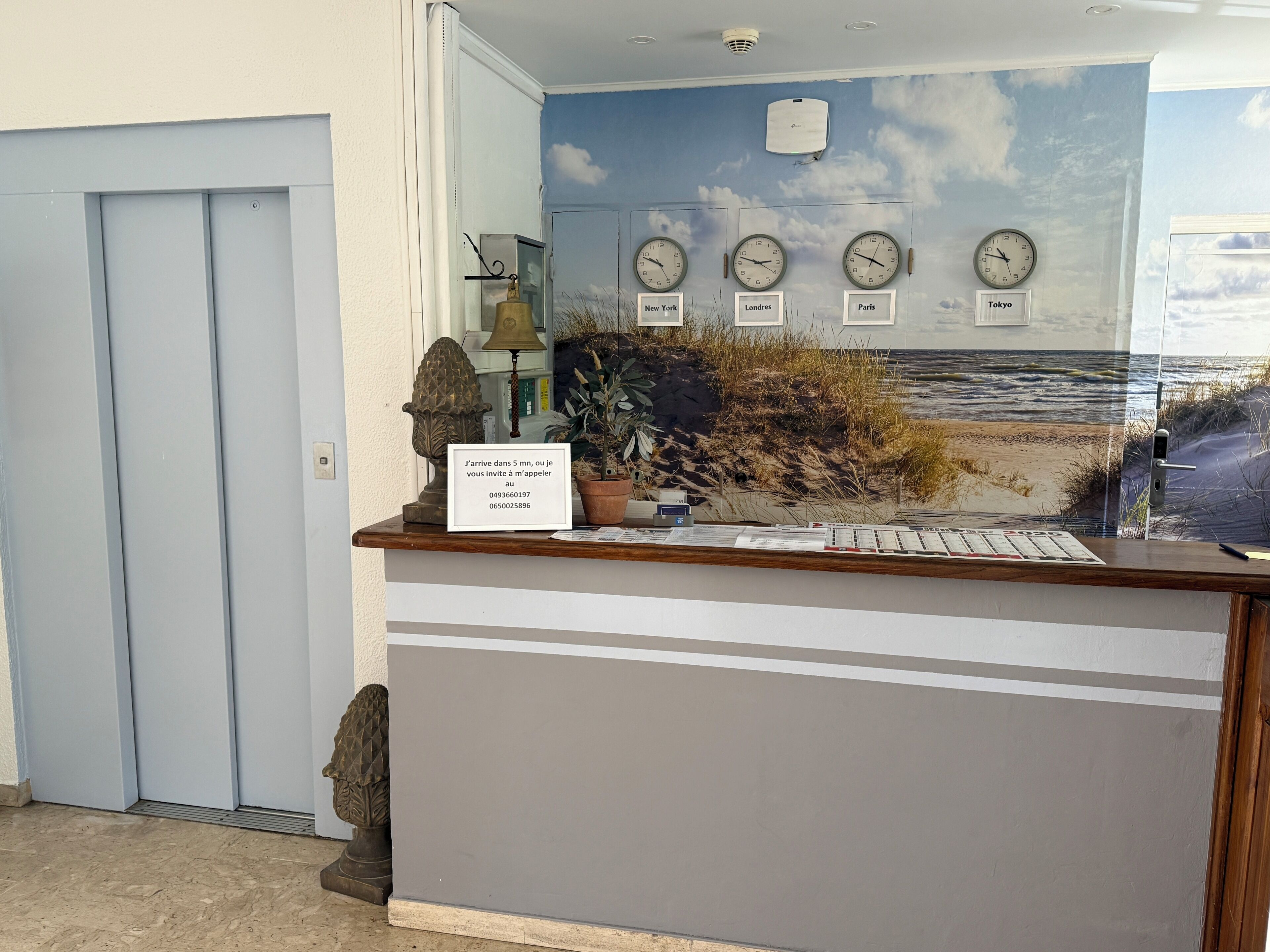 A reception desk with clocks showing different cities, a welcome sign, and a beach mural.