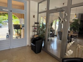 Un interior moderno con entrada de puerta de cristal, un área de estar con sillas negras y un espacio de comedor con mesa y sillas.