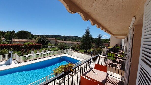 A poolside view with a clear blue pool, white sun loungers, and a balcony with a railing. - Hôtel de la Poste (Peymeinade)
