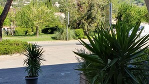 A paved entrance with potted plants, a clear view of a hilly landscape, and a distant building. - Hôtel de la Poste (Peymeinade)