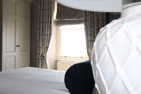 Une chambre d’hôtel avec un lit, des rideaux, une fenêtre et un radiateur.