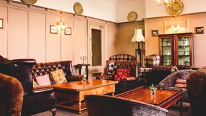 Una habitación tradicional con un sofá de cuero, una mesa de centro de madera y un sillón a cuadros.