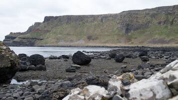 Una playa rocosa con grandes rocas y un acantilado al fondo.