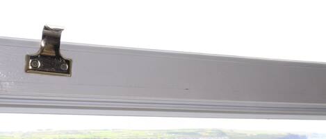 Ein Fensterriegel an einem weißen Fensterrahmen.