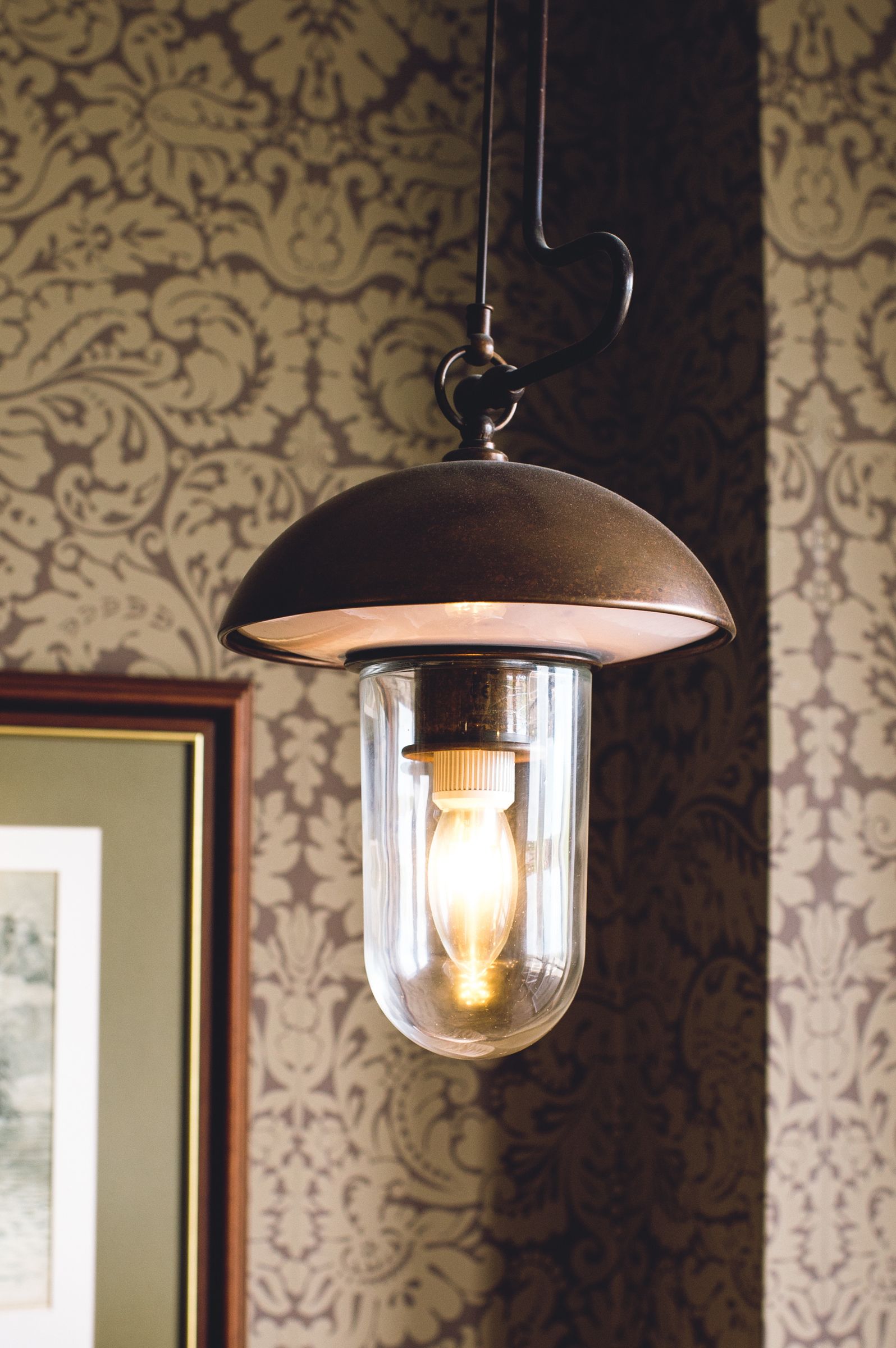 A hanging pendant light fixture with a clear glass enclosure and a visible light bulb.
