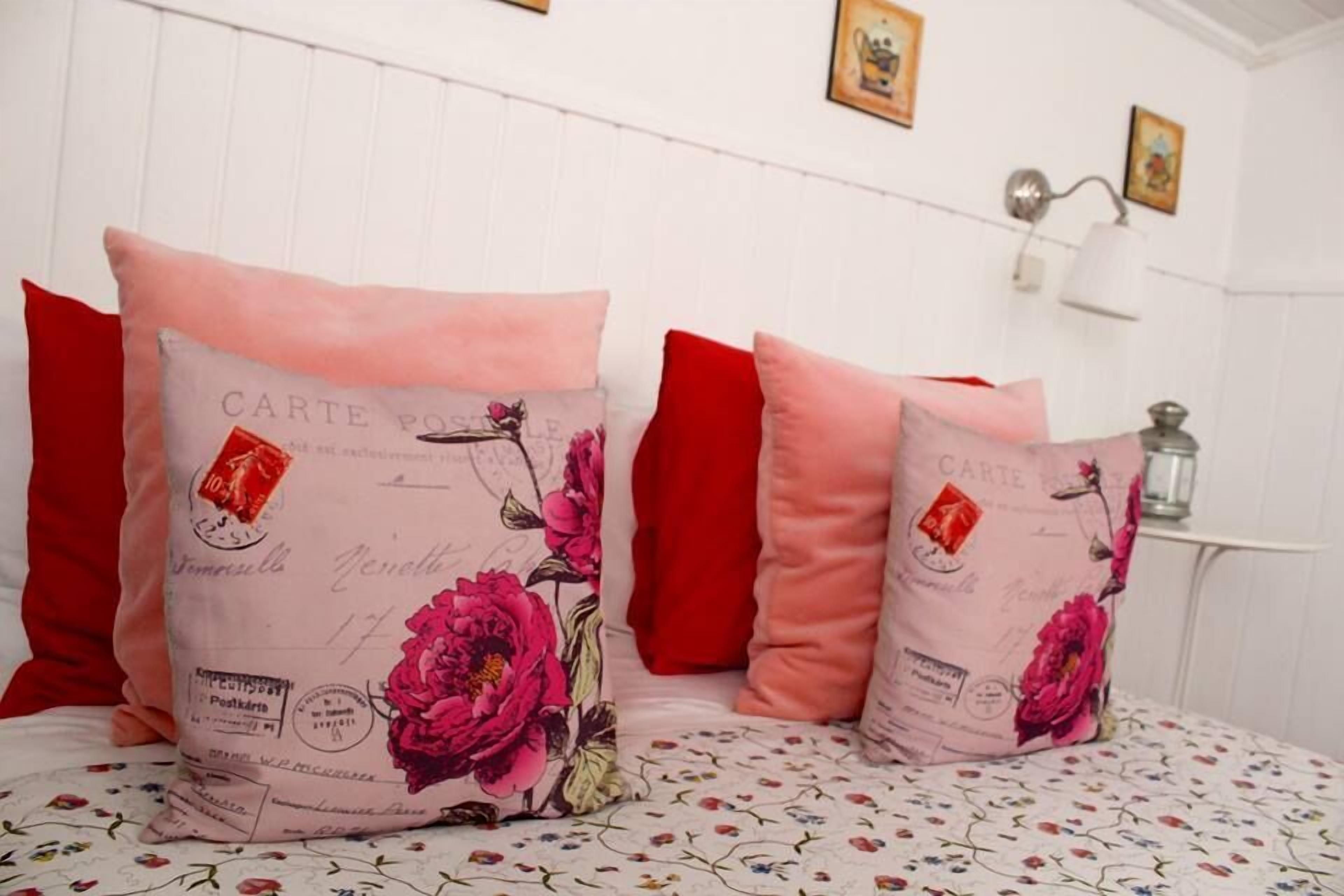 Een bed met twee sierkussens, versierd met een bloemmotief en de tekst 'CARTE'.