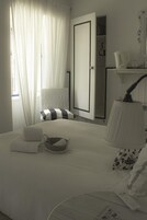 Un dormitorio con cama, mesita de noche, lámpara, sillón y armario.