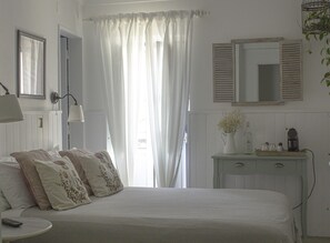 A bedroom with a bed, a nightstand, a dresser, a mirror, and a window with curtains. - Vinnus Guesthouse (Mafra)