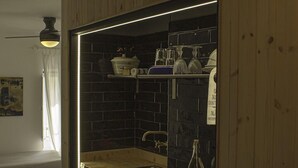 Una cocina compacta con muebles de madera, protector contra salpicaduras negro y microondas integrado.
