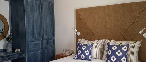Un dormitorio con una cama grande, un armario, una mesita de noche con lámpara y aire acondicionado instalado en la pared.