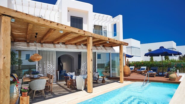 A poolside area with a wooden pergola, lounge chairs, and a pool. - Nausicaa Luxury Villas By Louis Hotels (Paralimni)