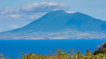 A mountain with a clear view of the ocean and a rocky foreground.