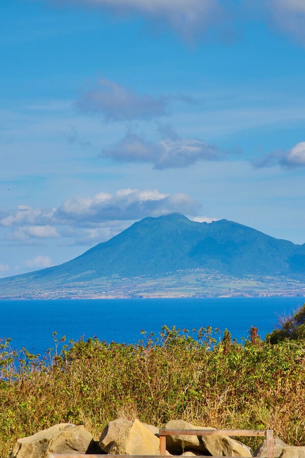 A mountain with a clear view of the ocean and a rocky foreground.