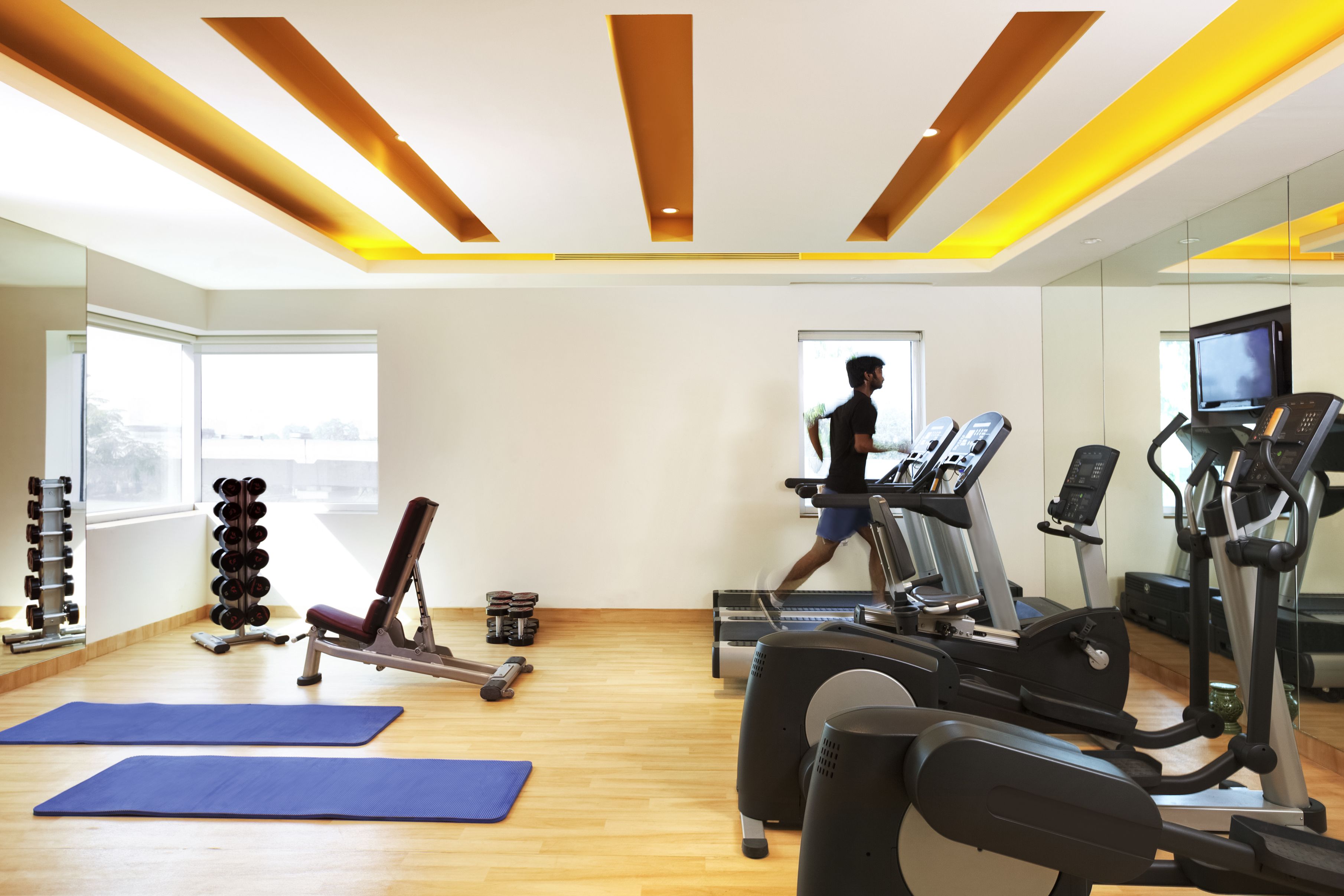 Een sportschool met trainingsapparatuur, yogamatten en een loopband.