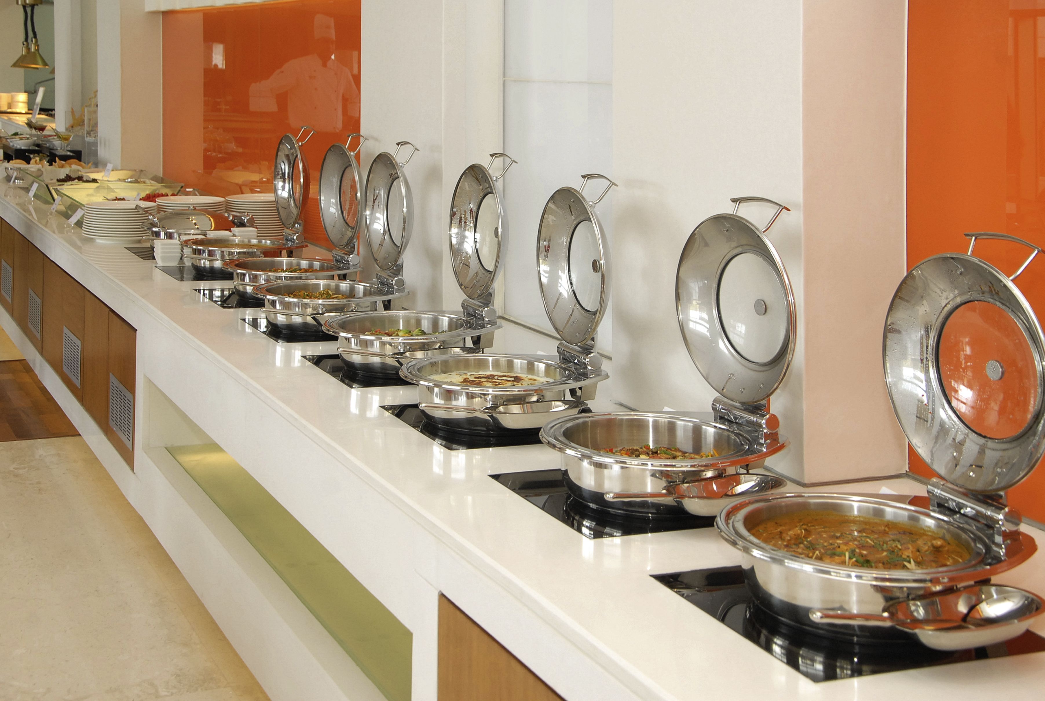 A buffet setup with multiple stainless steel serving dishes on a white counter.
