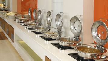 A buffet setup with multiple stainless steel serving dishes on a white counter.