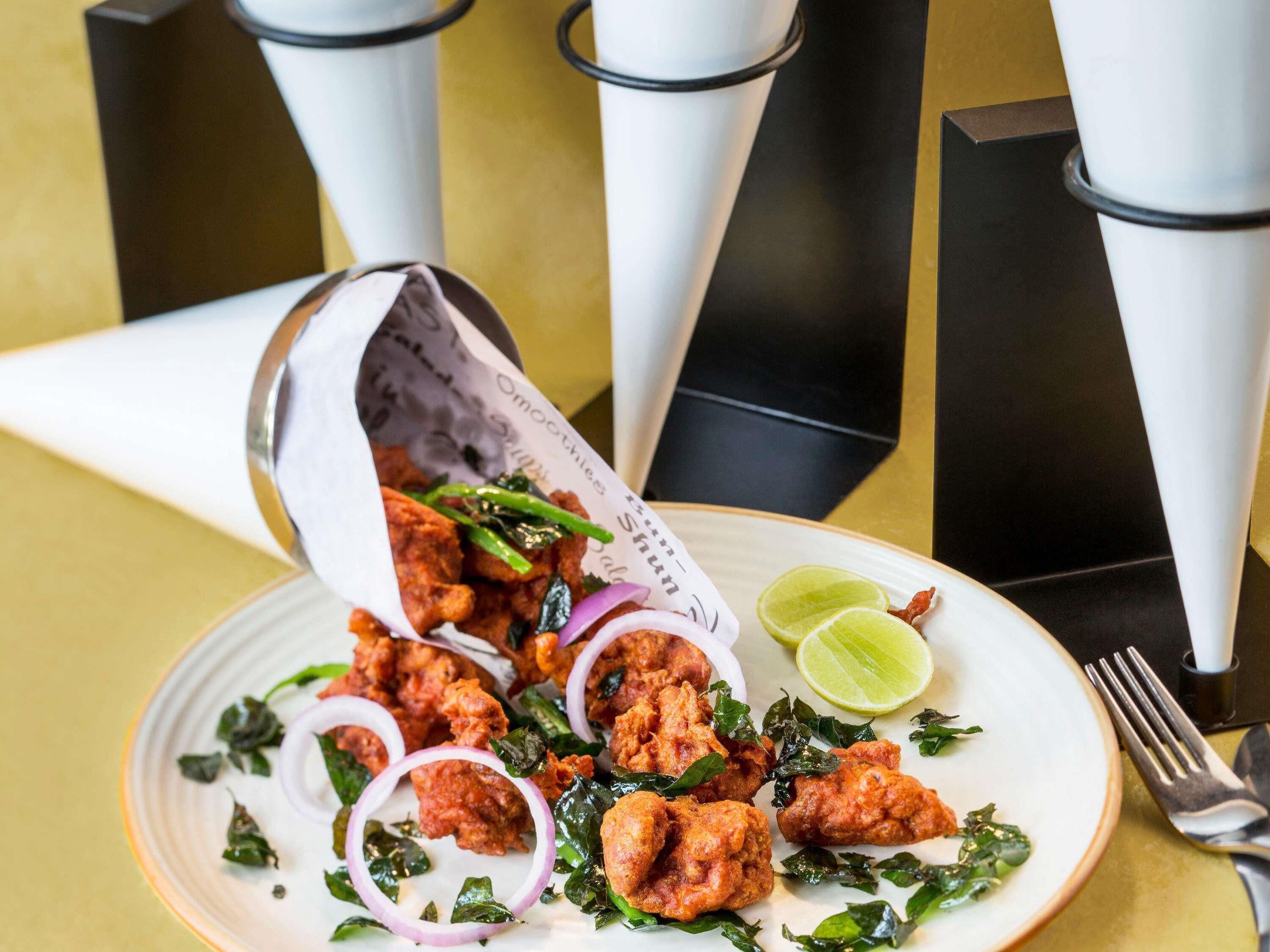 Un plato de pollo frito con cebollas y lima sobre una mesa.
