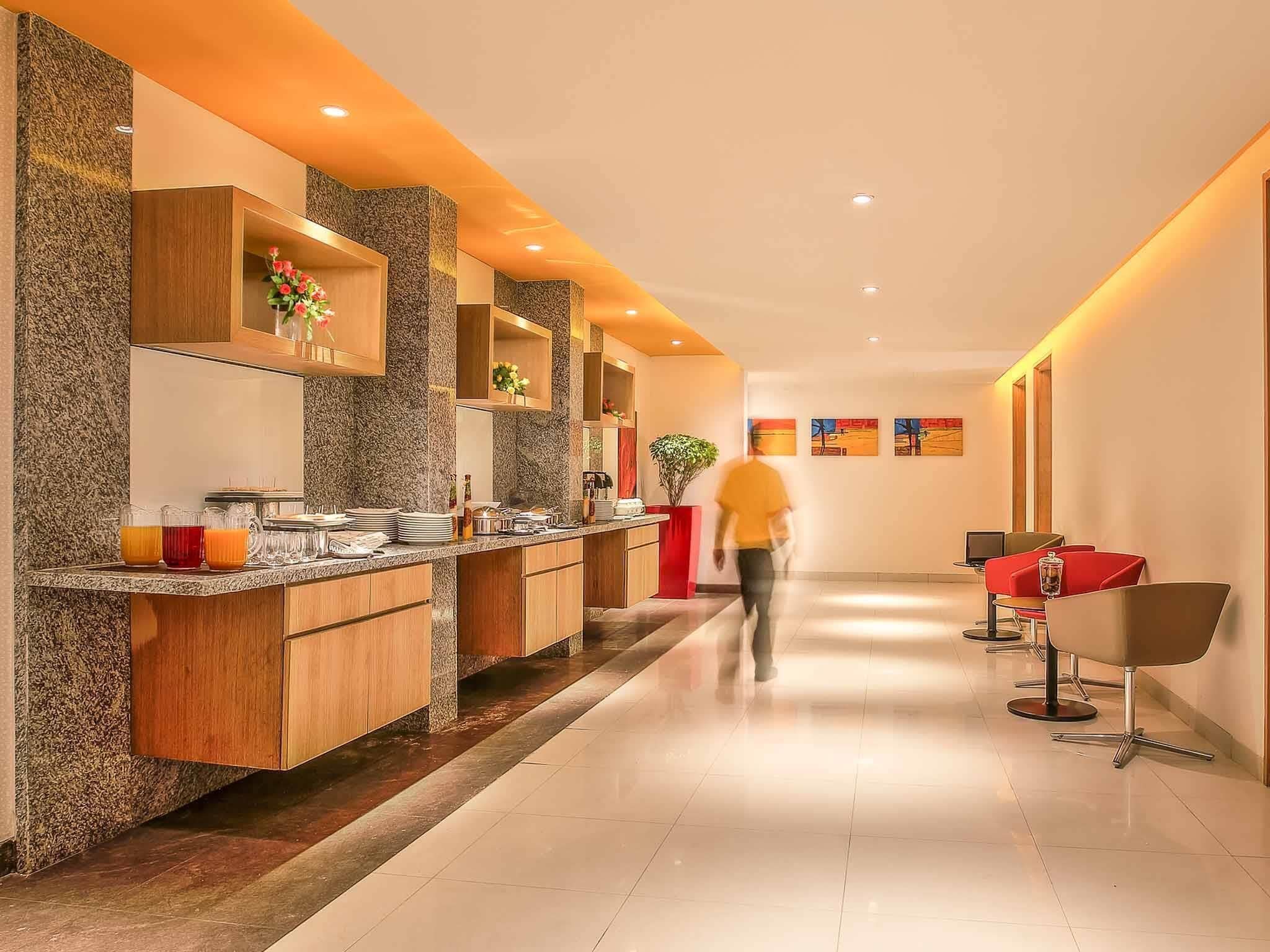 A modern hotel lobby with a long reception desk, wooden cabinets, and a tiled floor.
