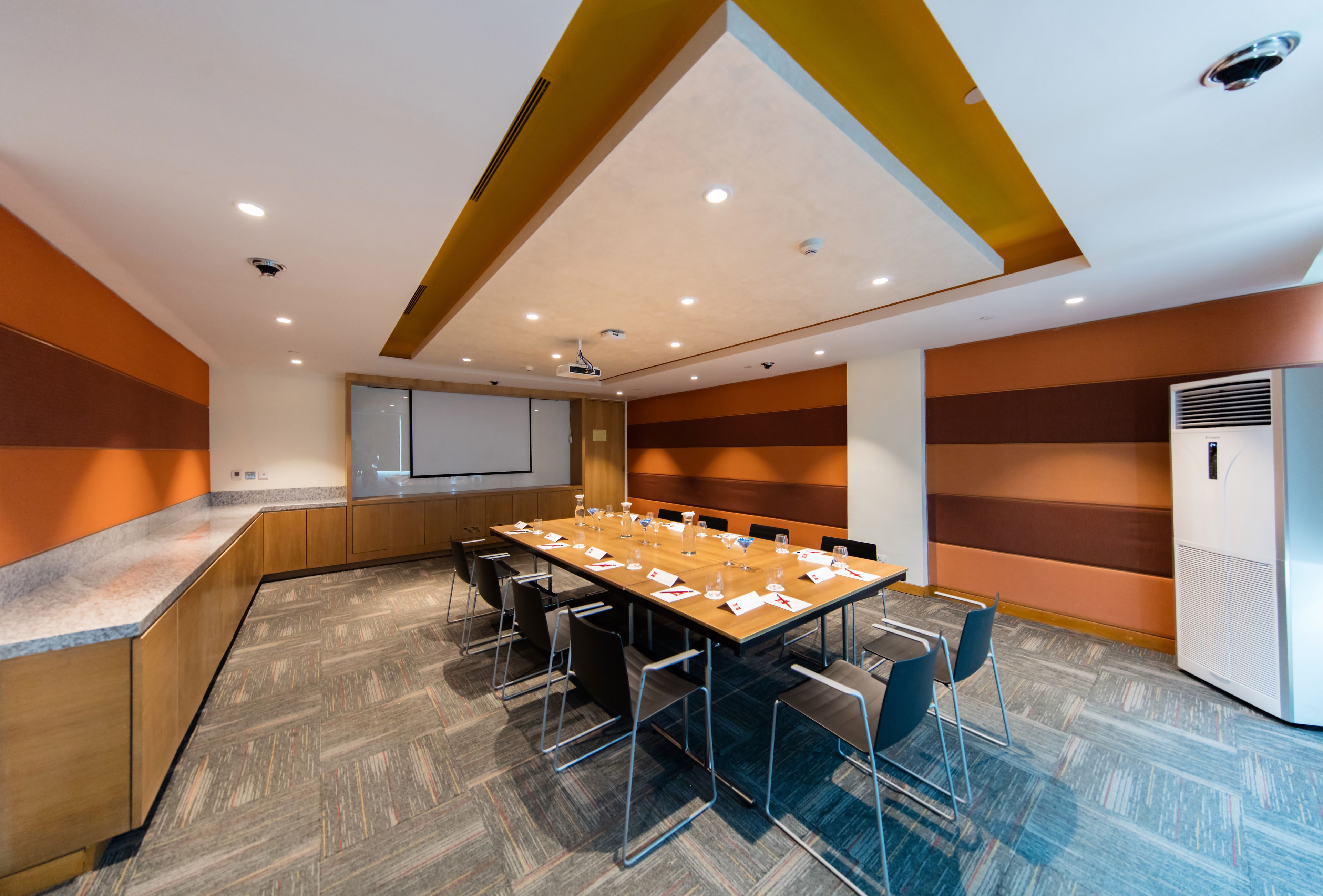 A conference room with a long table, chairs, a projector screen, and a whiteboard.