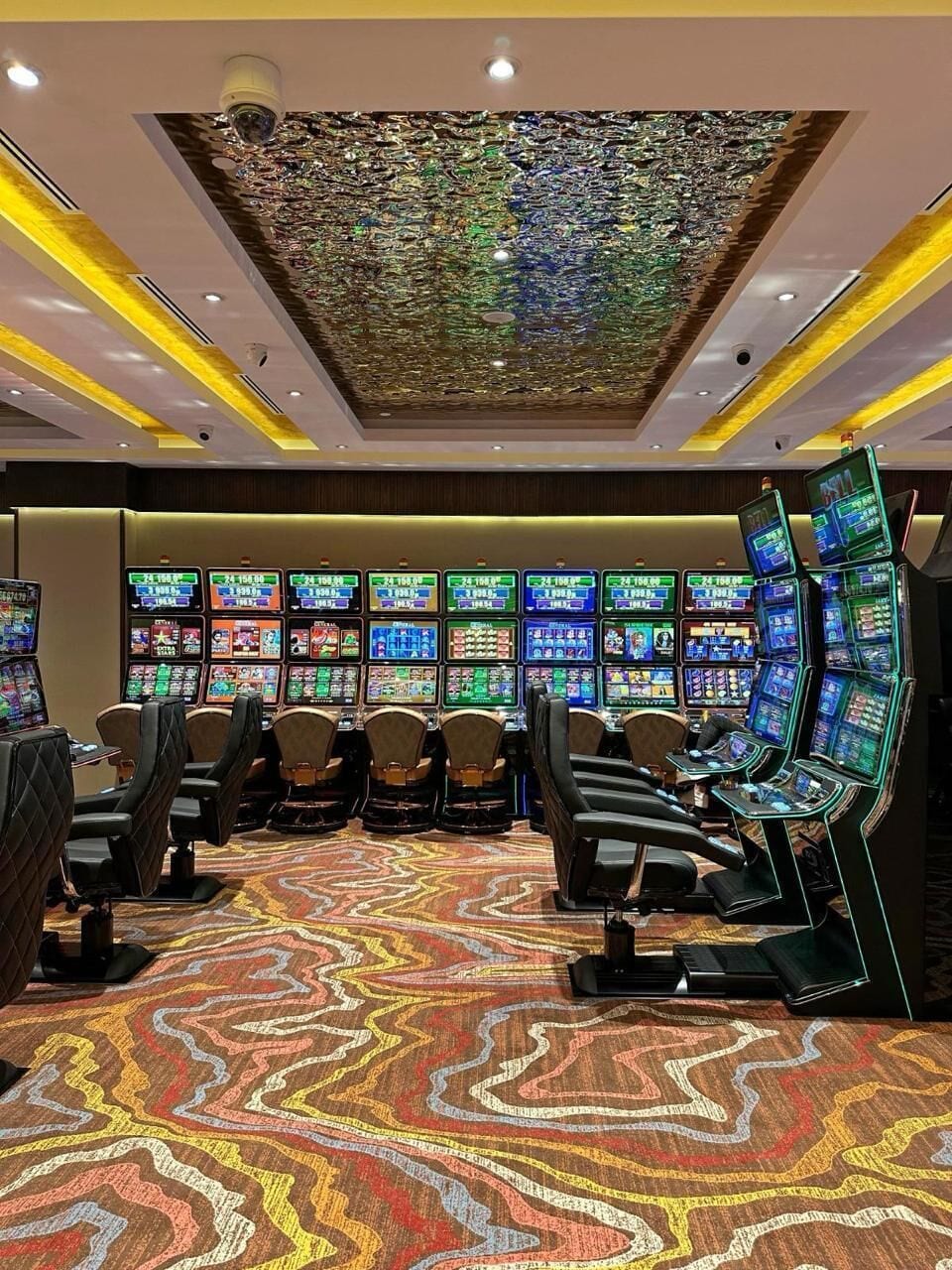 A gaming area with multiple screens, comfortable seating, and a patterned carpet.