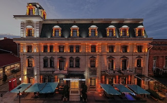 Un hotel histórico con una fachada clásica, varios balcones y zonas de estar al aire libre.
