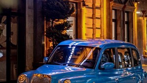A blue car parked in front of a hotel with a neon sign that reads "LONDON 1889 HOTEL". - Hotel London 1889 & Casino (Batumi)