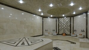 A spacious, well-lit spa area with a large, octagonal marble tub, decorative wall panels, and several small, round, white planters. - Hotel London 1889 & Casino (Batumi)