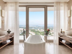 A modern bathroom with a freestanding bathtub, large windows, and a city view.