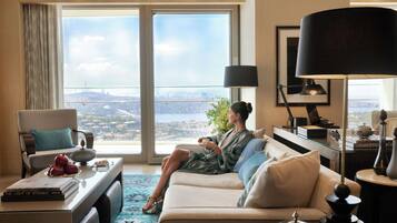 A room with a large window, a sofa, a coffee table, and a desk with a lamp.