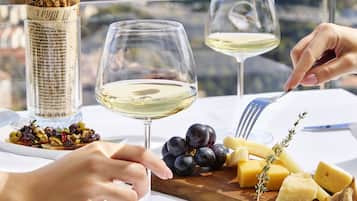 A table set with cheese, grapes, crackers, and a bowl of jam, with a scenic view in the background.
