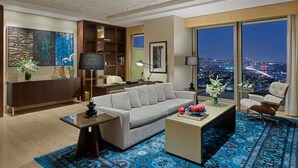 Una sala de estar moderna con un sofá, una mesa de centro y vistas a un paisaje urbano nocturno.