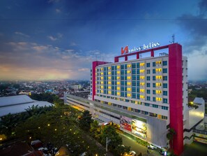 A multi-story hotel with a prominent red and white facade, large windows, and a view of the surrounding cityscape. - Swiss-Belinn Malang (Malang)