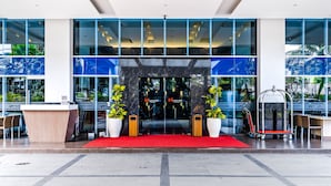 A hotel entrance with a red carpet, large windows, and potted plants. - Swiss-Belinn Malang (Malang)