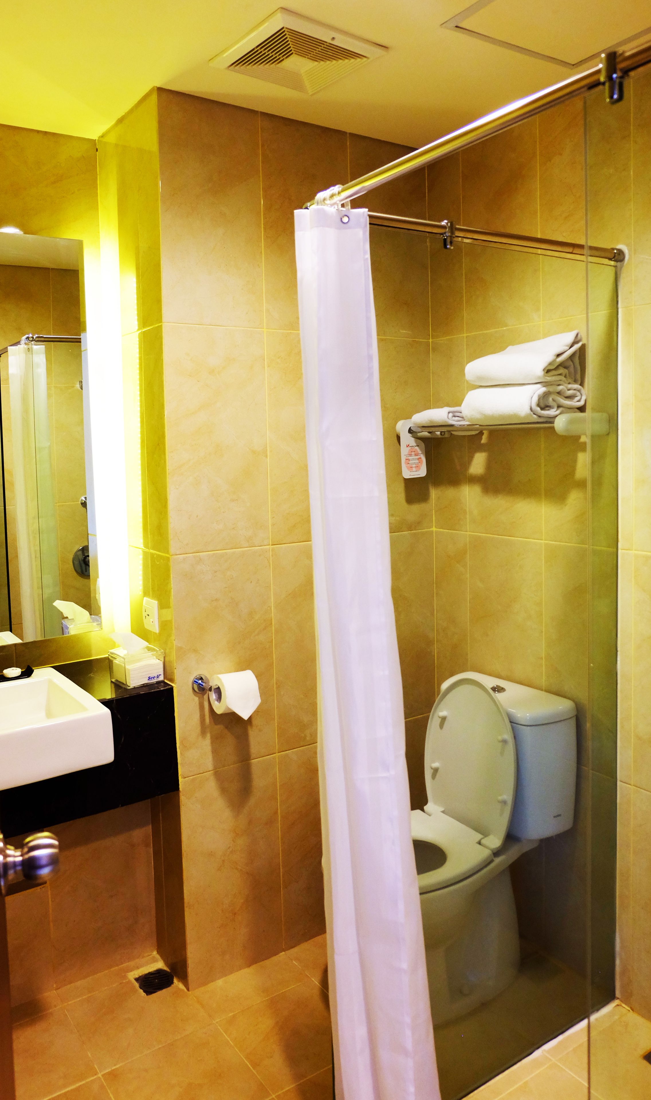 A bathroom with a glass shower enclosure, a toilet, and a sink with a mirror.