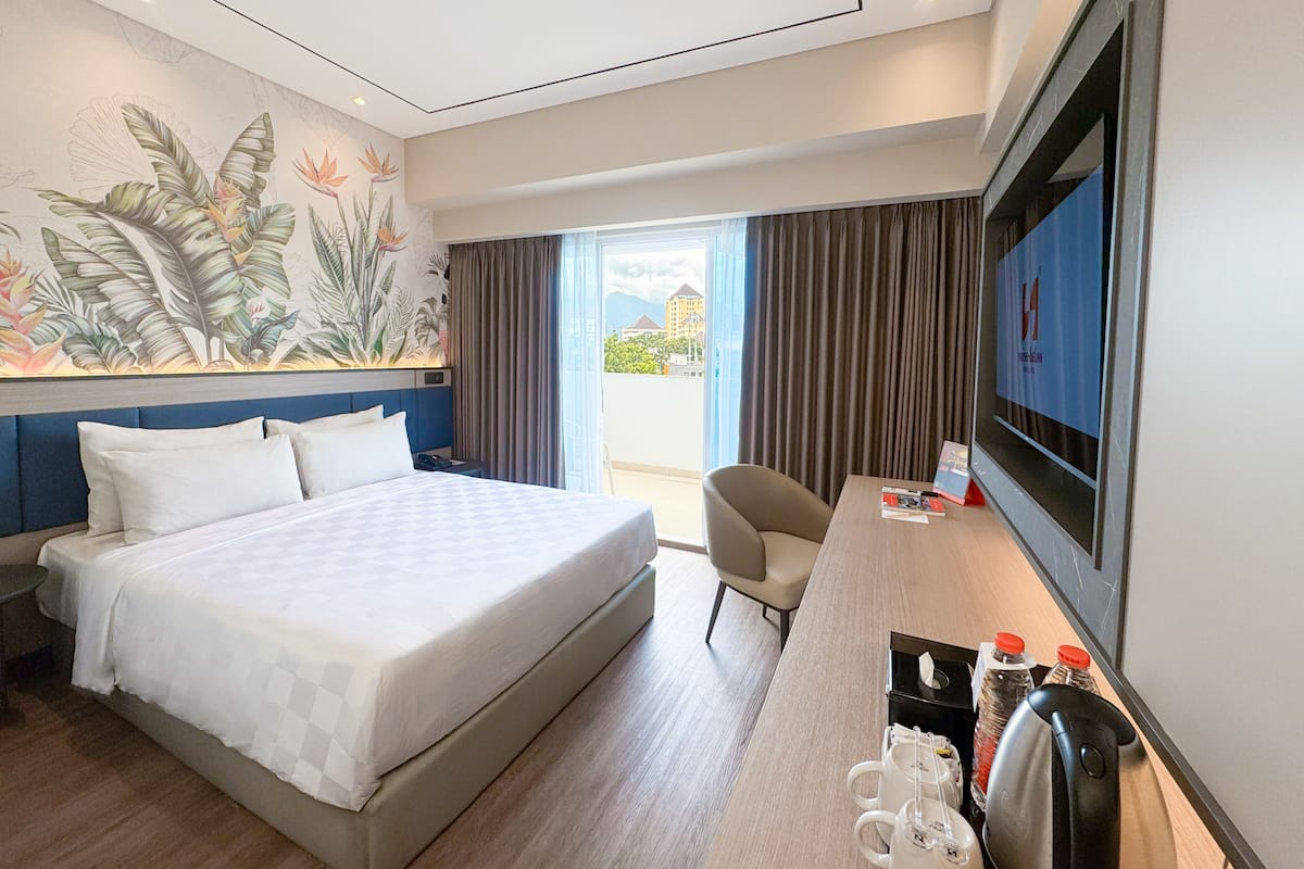 Une chambre d’hôtel équipée d’un lit, d’un bureau, d’une chaise, d’une télévision et d’une fenêtre avec des rideaux.