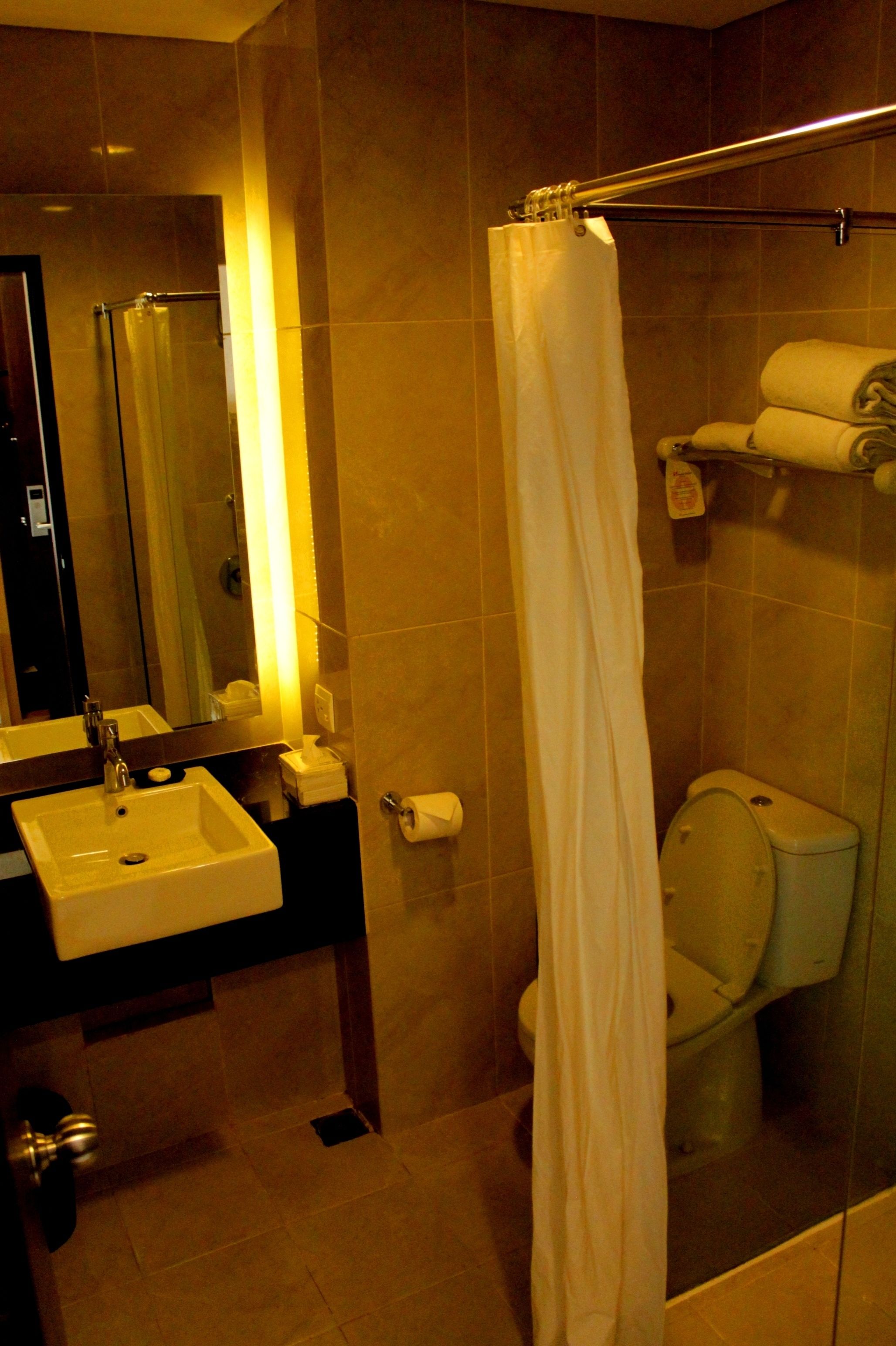 Ein Badezimmer mit Waschbecken, Spiegel, Toilette und Duschvorhang.