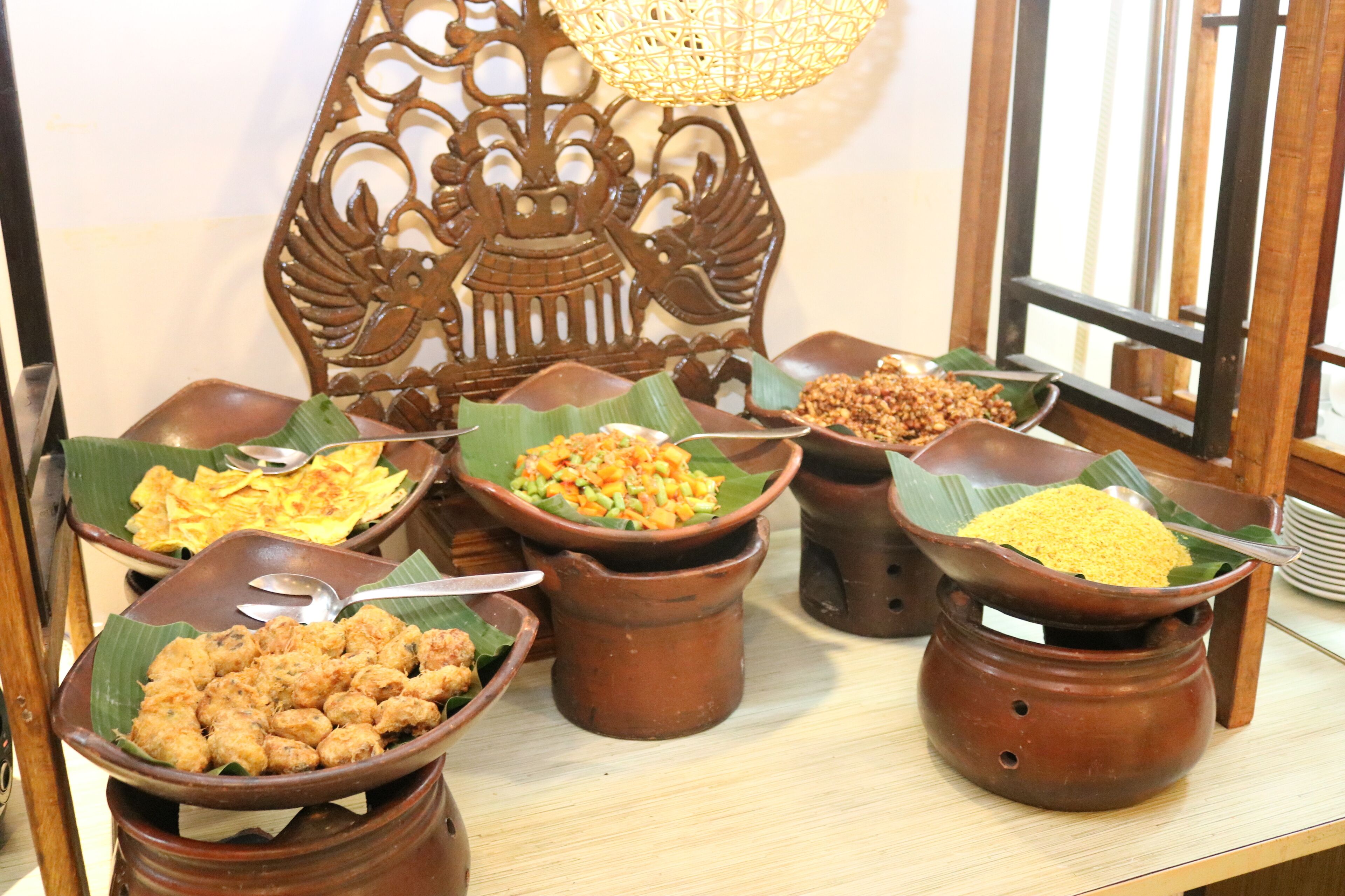 Una mesa con diversos alimentos servidos en ollas de barro tradicionales y hojas de plátano.