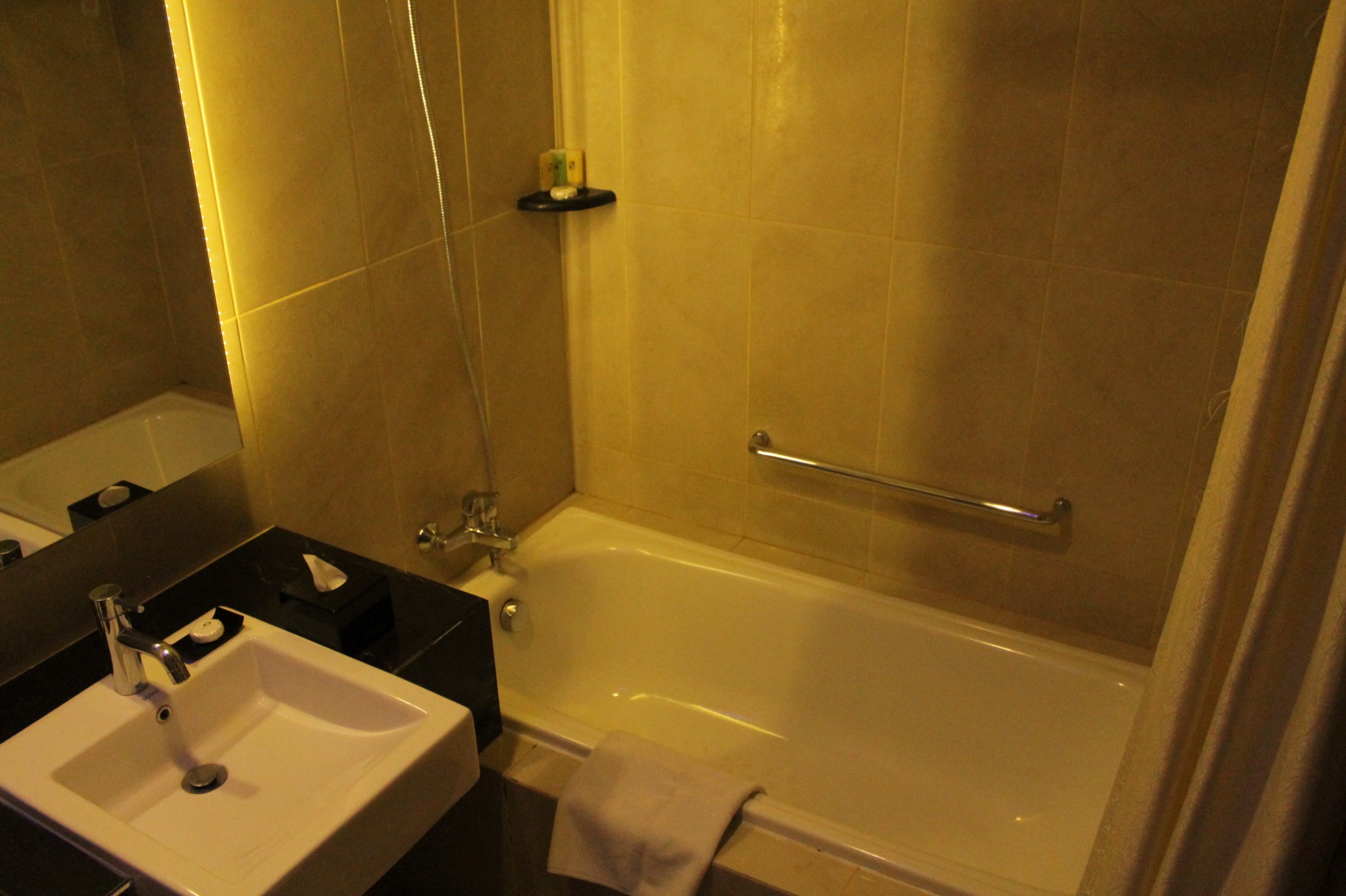 A bathroom with a sink, mirror, and bathtub.