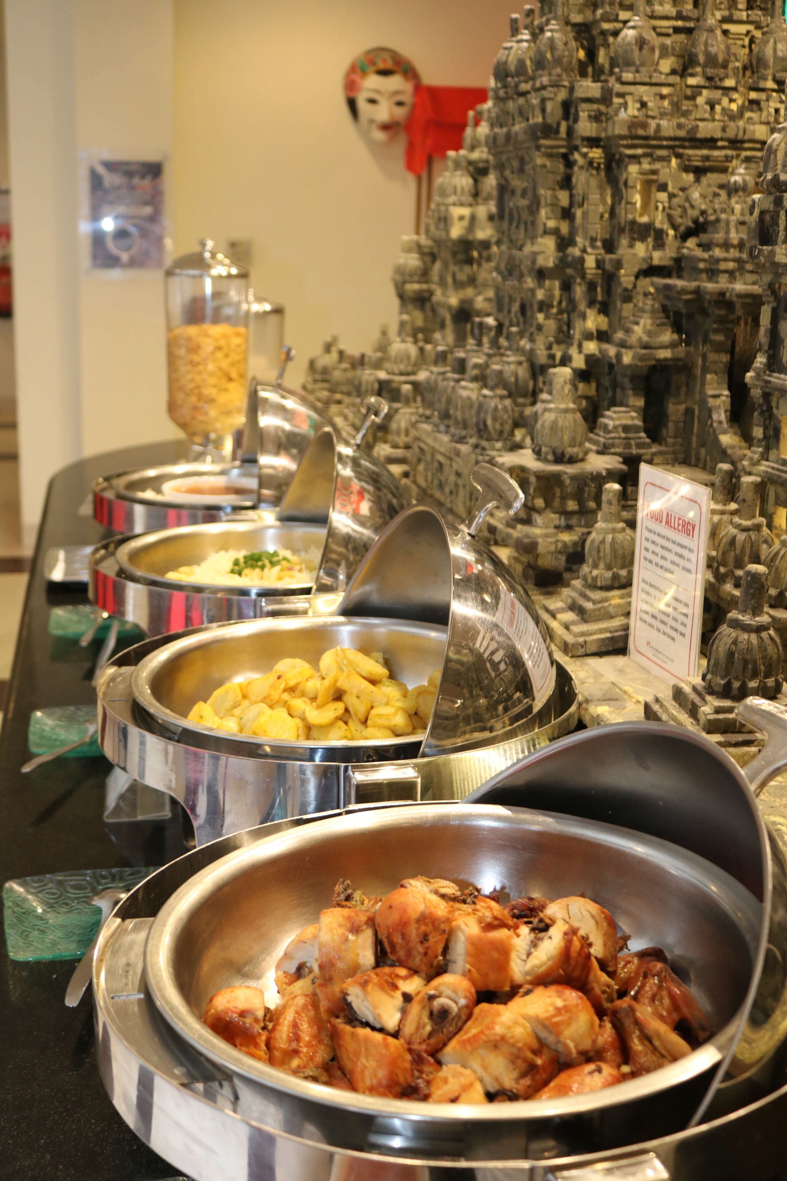 A buffet with various food options, including a bowl of chicken and a container of what appears to be rice.