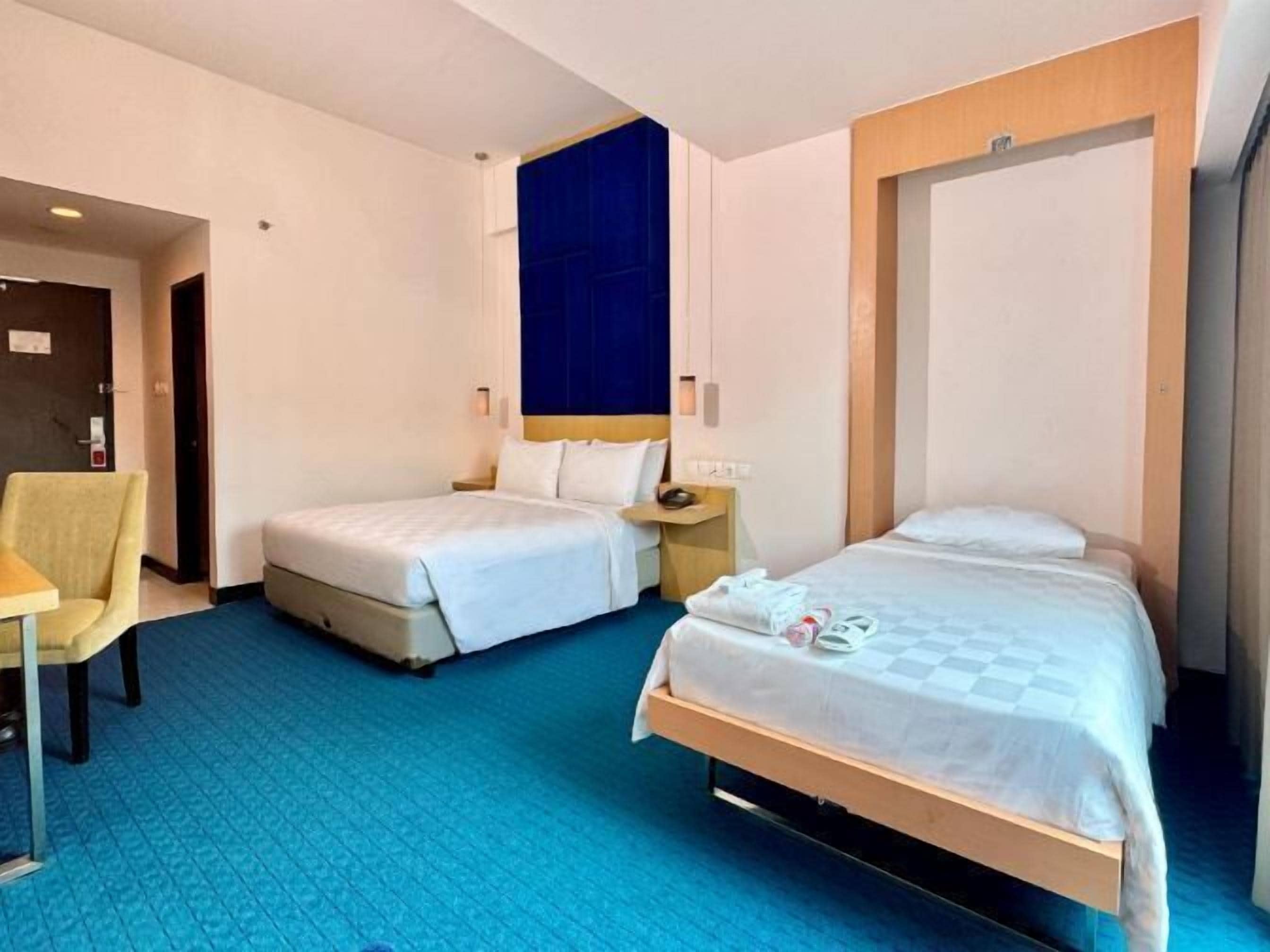 A hotel room with two beds, a desk, and a chair.