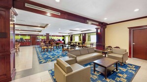 Tilava aula, jossa on oleskelualue, taustalla keittiö ja oikealla puolella ovi.