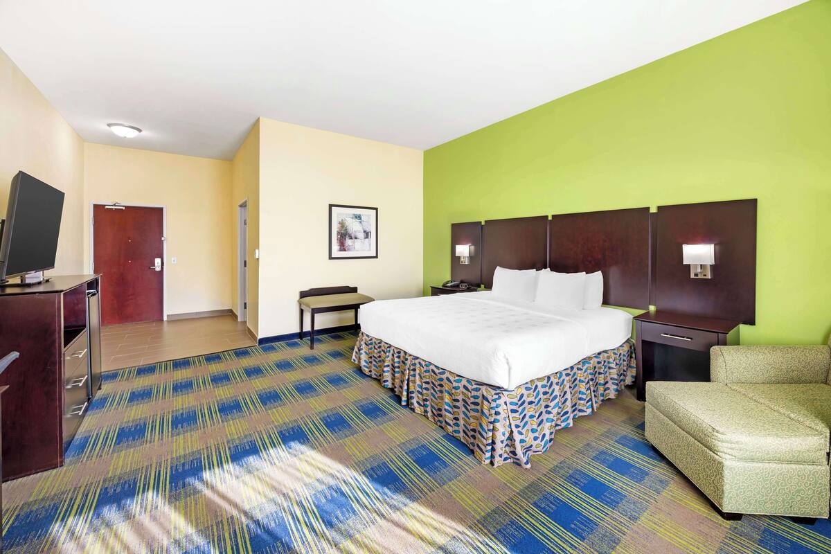 Habitación de hotel con una cama grande, un escritorio, una silla y una televisión.