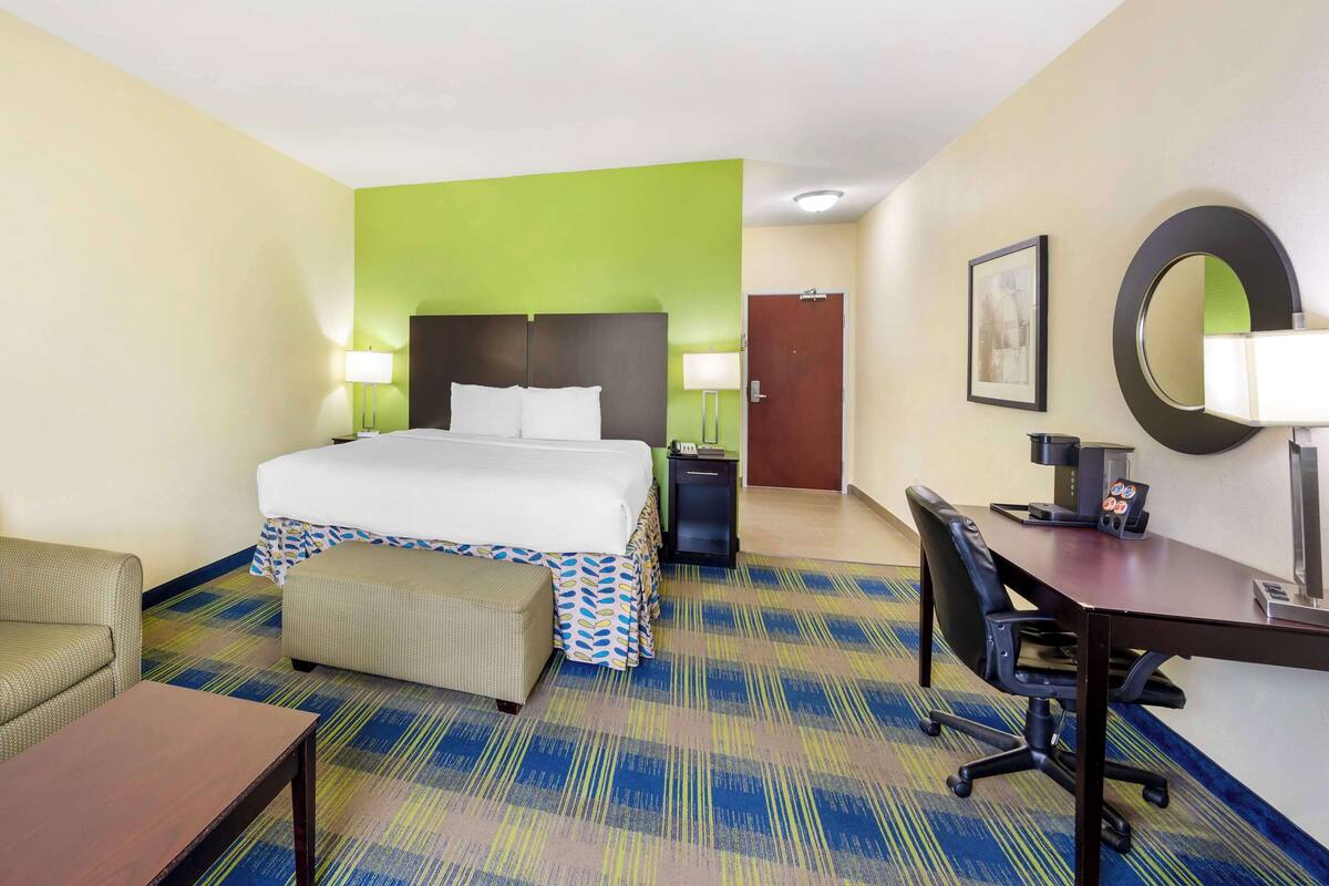 Una habitación de hotel con cama, escritorio, silla y una mesita.