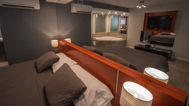 A modern hotel room with a large bed, a separate bathroom with a bathtub, a flat-screen TV, and a large mirror. - Gables Cove Hotel (Coral Gables)